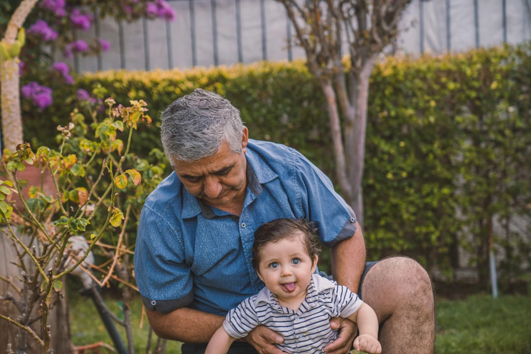 Grandfather holding a baby in a garden